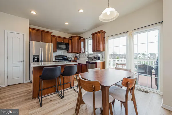 a kitchen with stainless steel appliances granite countertop a stove a refrigerator a sink a dining table and chairs with wooden floor