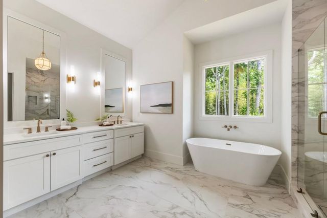a spacious bathroom with a double vanity sink large mirror a bathtub and next to a window
