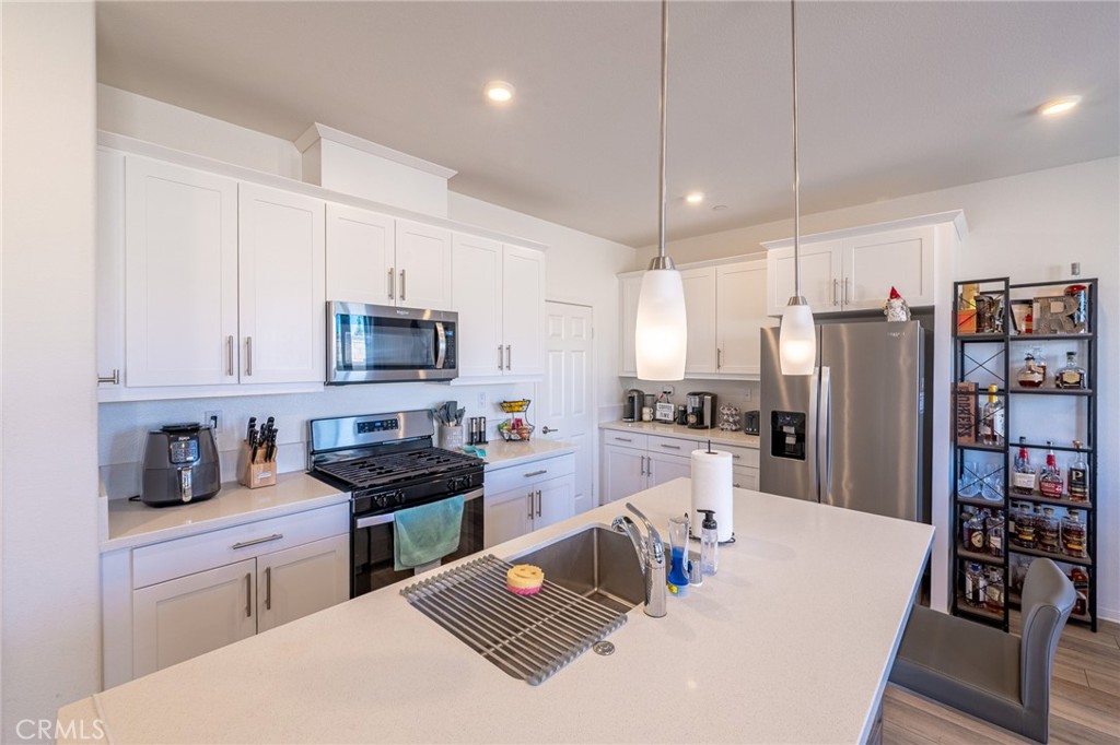 202 Bonita Lane Rialto, CA 92376 - Photo 13 of 43 a kitchen with stainless steel appliances granite countertop a sink dishwasher a refrigerator and white cabinets with wooden floor