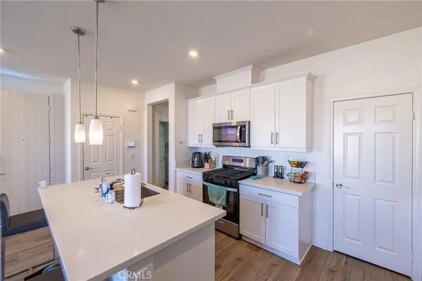 a kitchen with stainless steel appliances a white table chairs and a refrigerator