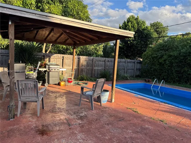 an outdoor sitting area with a table and chairs under an umbrella