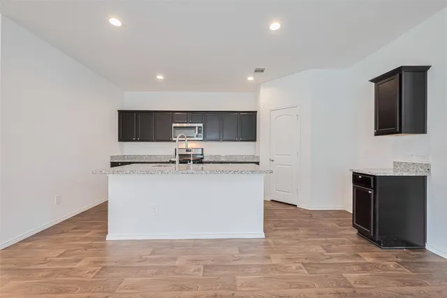 a view of kitchen with stainless steel appliances granite countertop cabinets and wooden floor
