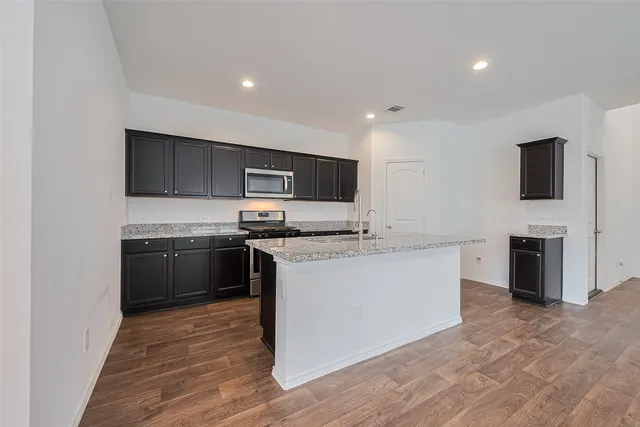 a kitchen with stainless steel appliances kitchen island granite countertop a stove a sink and a refrigerator