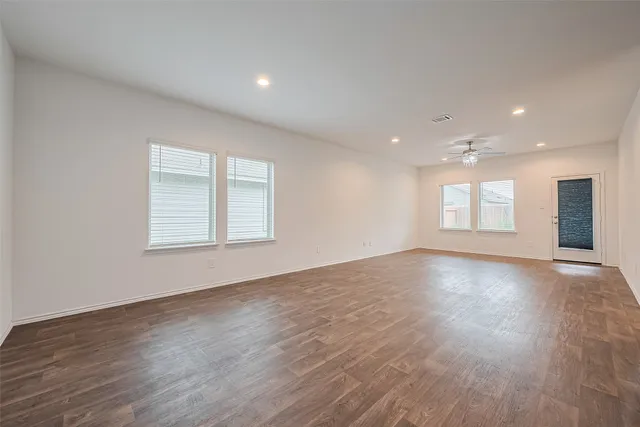 an empty room with wooden floor and windows