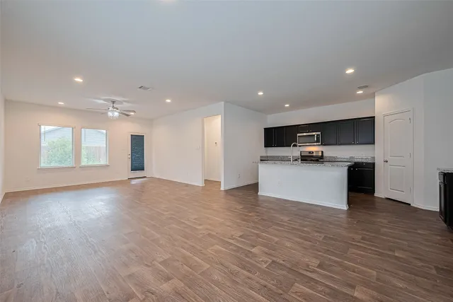 a view of kitchen with kitchen island wooden floors and stainless steel appliances