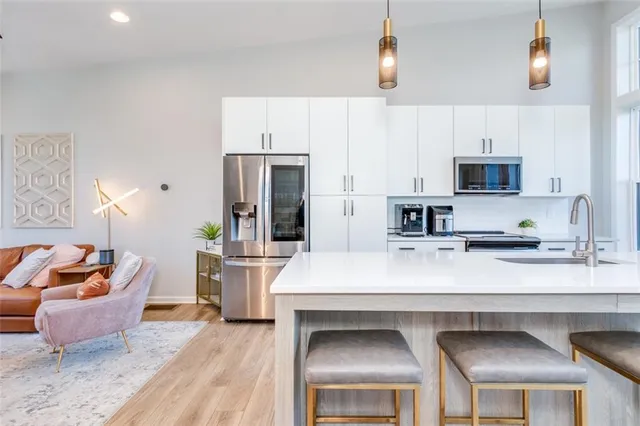 a kitchen with kitchen island a stove a sink a microwave a refrigerator and cabinets