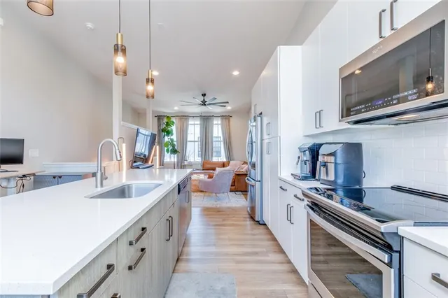 a large white kitchen with a stove a sink dishwasher and a refrigerator with wooden floor