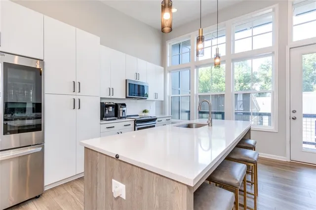 a kitchen with kitchen island a stove a sink a microwave a refrigerator and cabinets