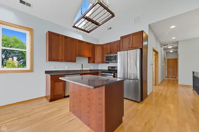 a kitchen with stainless steel appliances granite countertop a refrigerator a stove a sink and a microwave