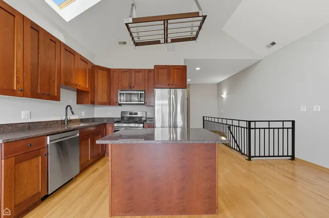 a kitchen with stainless steel appliances granite countertop a refrigerator a stove top oven a sink and dishwasher