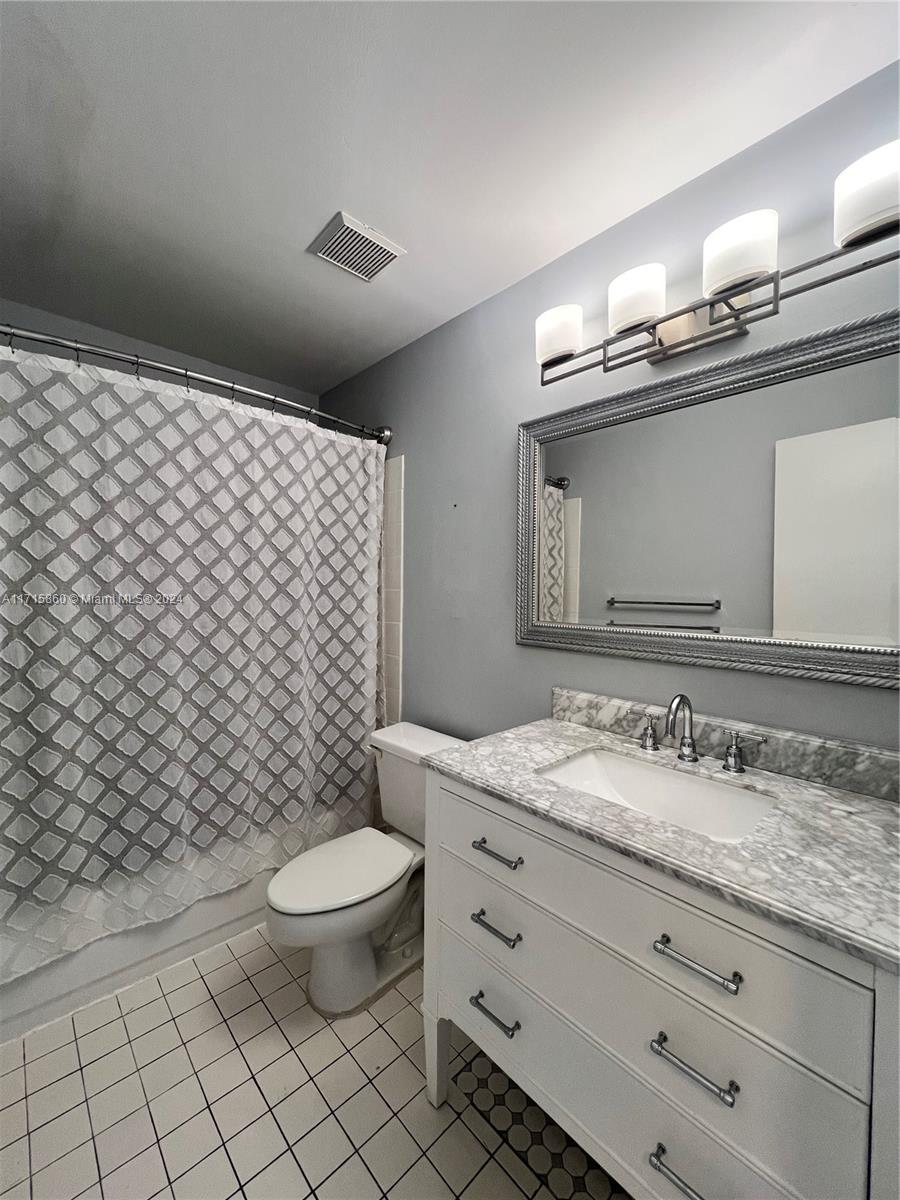 8281 Southwest 128th Street, Unit 213 Pinecrest, FL 33156 - Photo 2 of 8 a bathroom with a granite countertop toilet a sink and a mirror