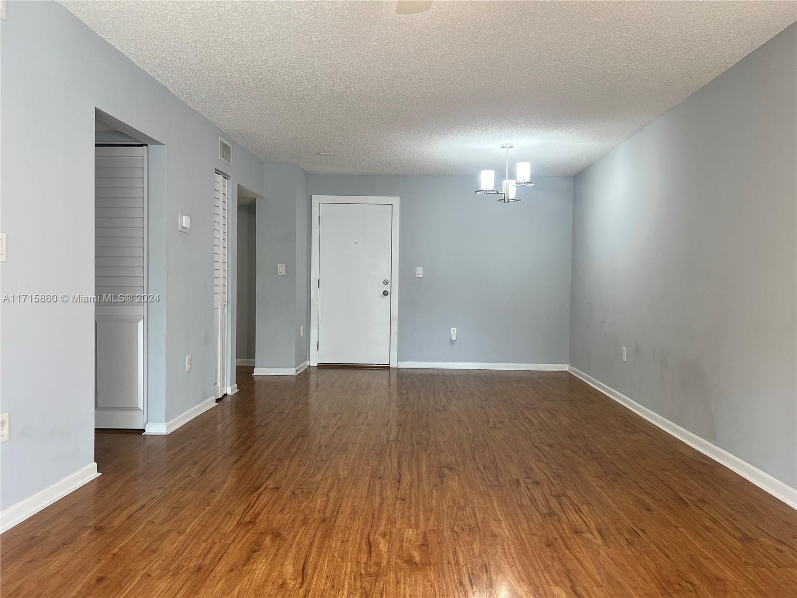 8281 Southwest 128th Street, Unit 213 Pinecrest, FL 33156 - Photo 3 of 8 a view of an empty room with wooden floor