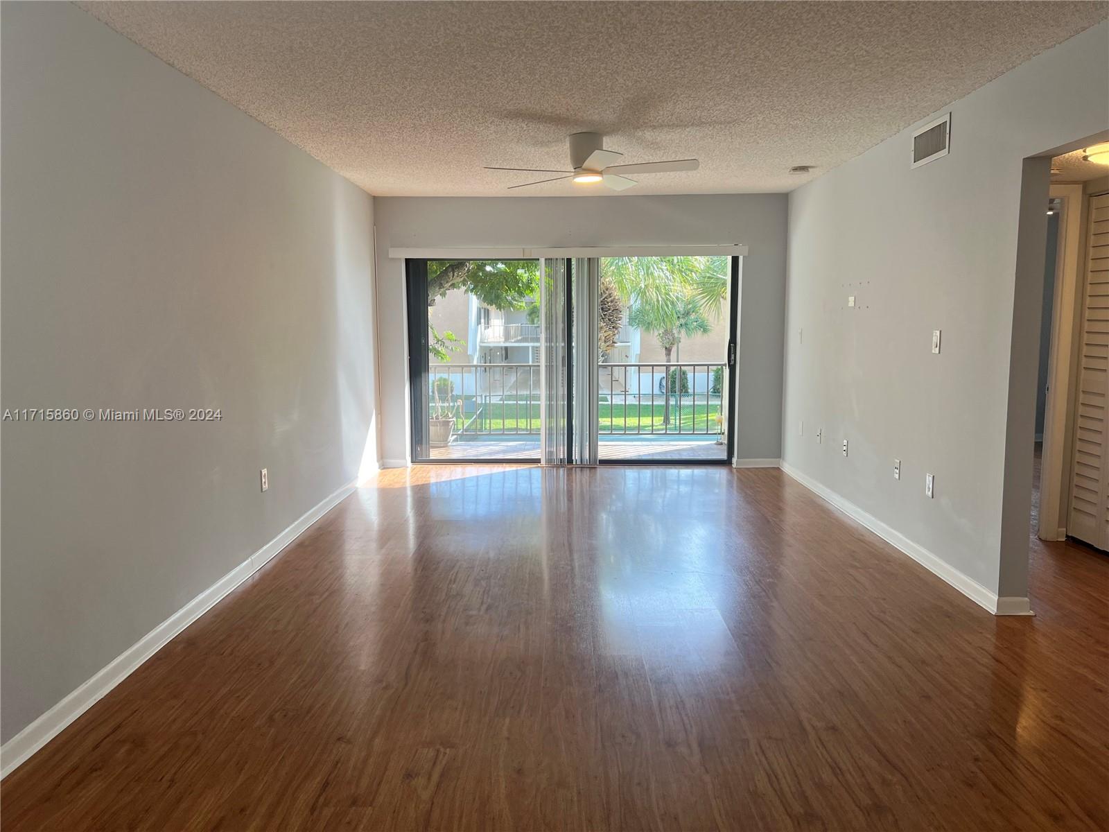 8281 Southwest 128th Street, Unit 213 Pinecrest, FL 33156 - Photo 4 of 8 an empty room with wooden floor and windows with curtains