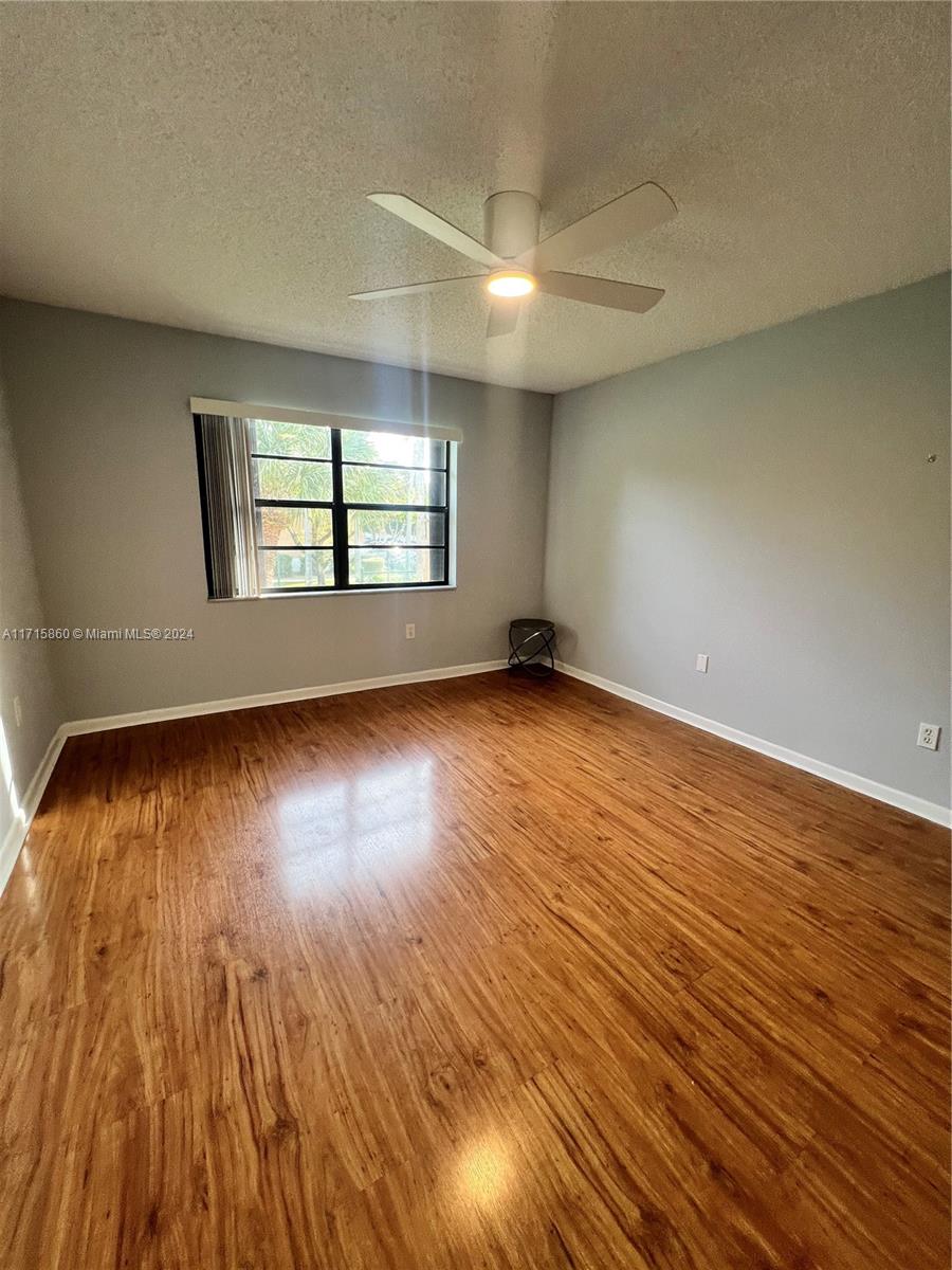 8281 Southwest 128th Street, Unit 213 Pinecrest, FL 33156 - Photo 5 of 8 an empty room with wooden floor and windows