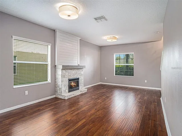 an empty room with windows a fireplace and wooden floor