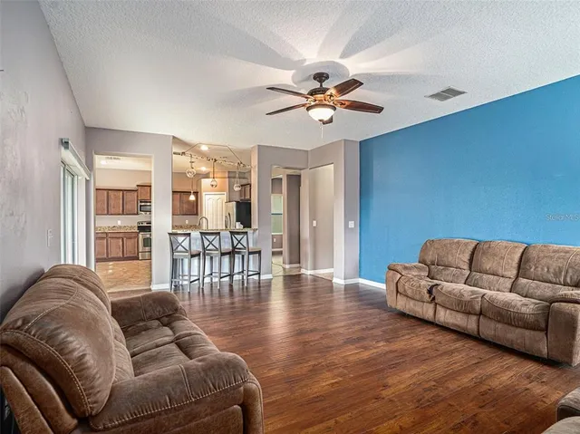 a living room with furniture ceiling fan and a wooden floor