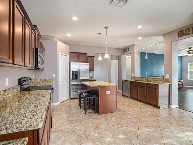 a kitchen with stainless steel appliances granite countertop a stove a sink a oven a dining table and chairs