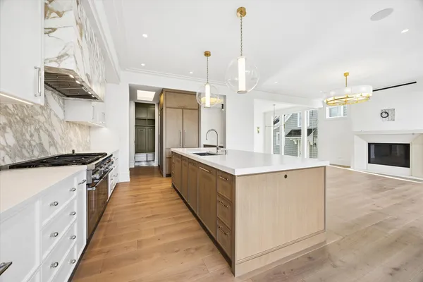 a large kitchen with kitchen island a stove a sink a center island and wooden floor