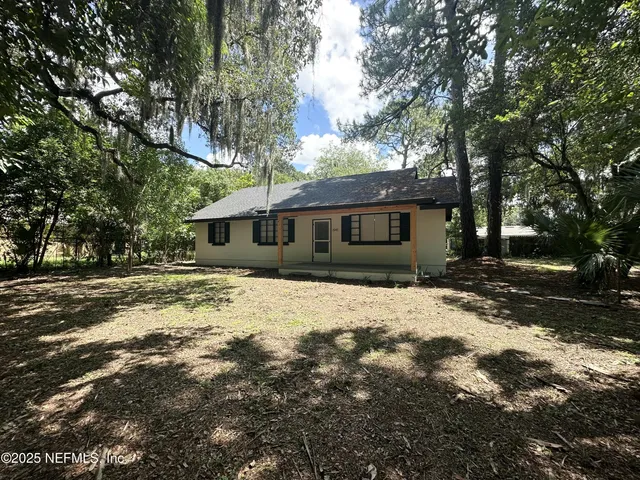 a front view of a house with a yard covered with trees