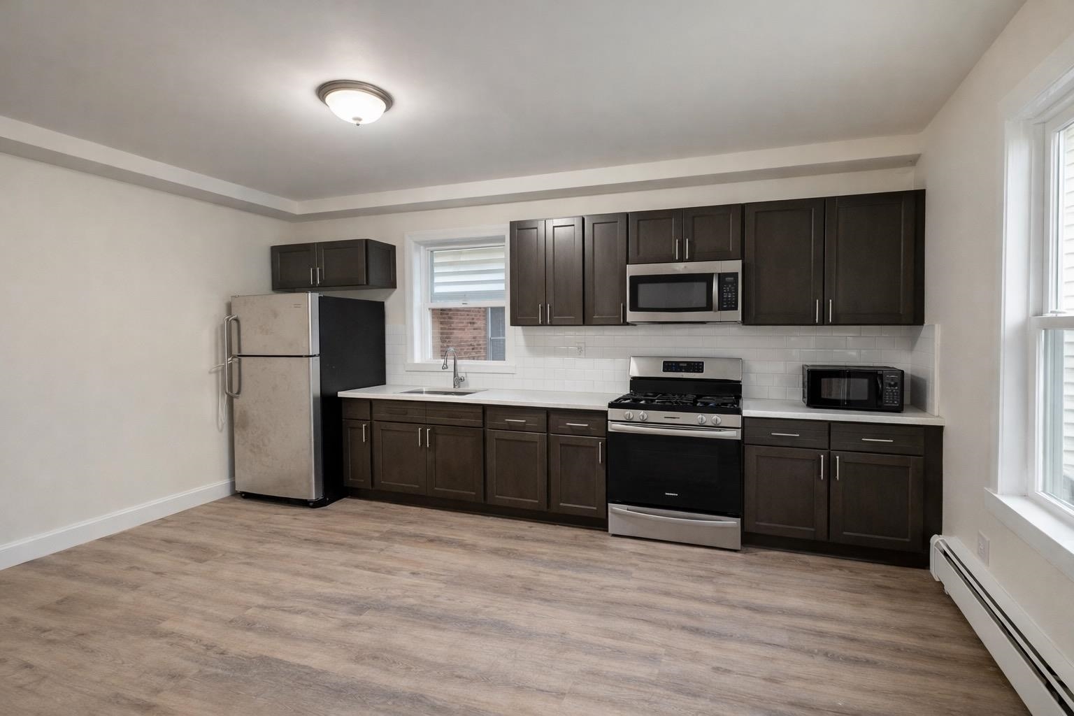 64 South 13th Street, Unit 2 Newark, NJ 07107 - Photo 2 of 11 a kitchen with granite countertop a refrigerator and a stove top oven