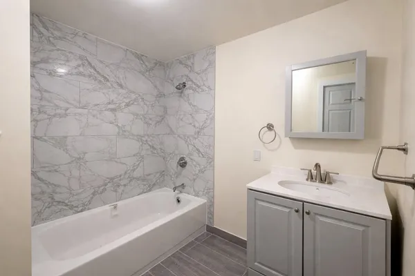 a bathroom with a sink a mirror a bathtub and shower