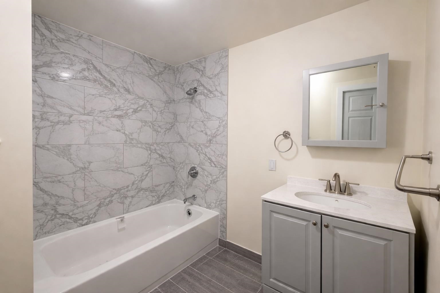 64 South 13th Street, Unit 2 Newark, NJ 07107 - Photo 3 of 11 a bathroom with a sink a mirror a bathtub and shower