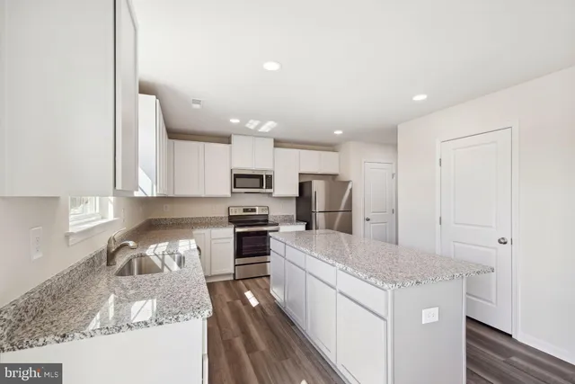a kitchen with granite countertop a sink stove and refrigerator