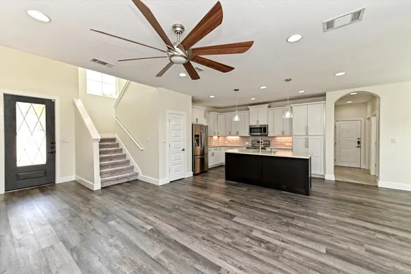 a living room with stainless steel appliances furniture and a kitchen view