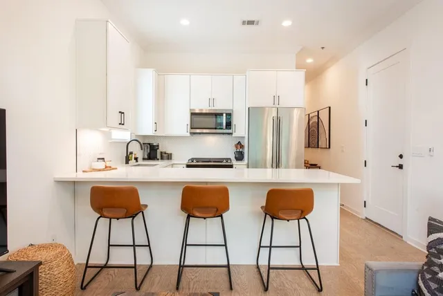 a kitchen that has a sink and a stove with the view of living room