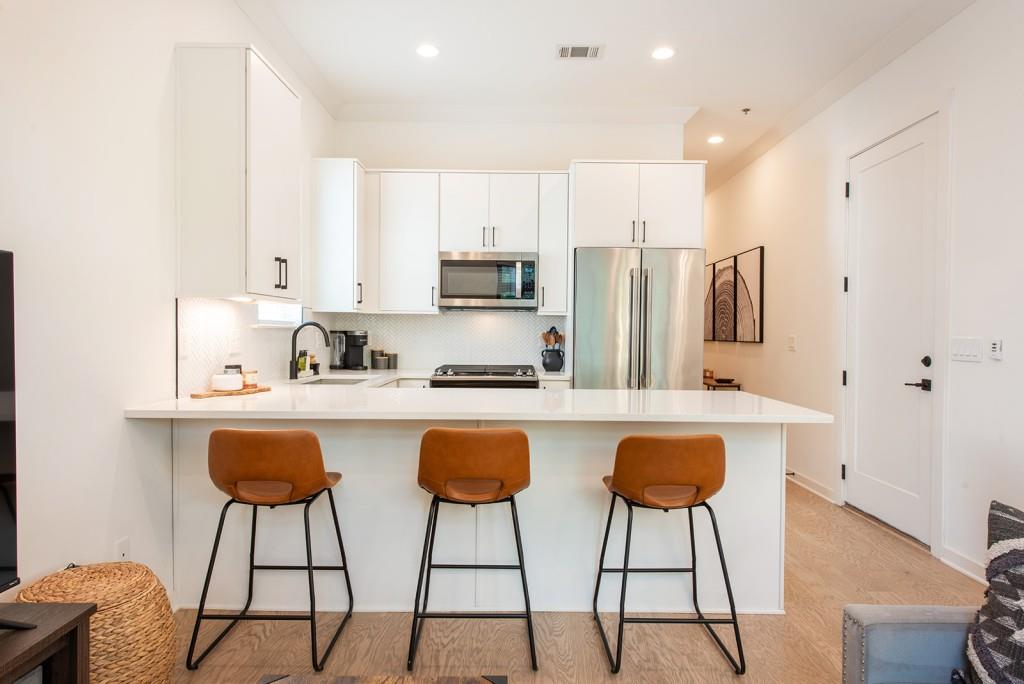 417 East College Avenue, Unit 102 Decatur, GA 30030 - Photo 11 of 60 a kitchen with stainless steel appliances granite countertop a table chairs sink and cabinets