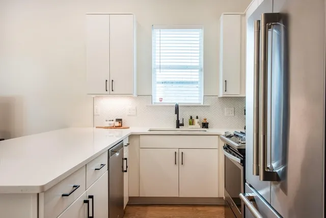 a kitchen with stainless steel appliances granite countertop a refrigerator a sink a stove a microwave and island with wooden floor