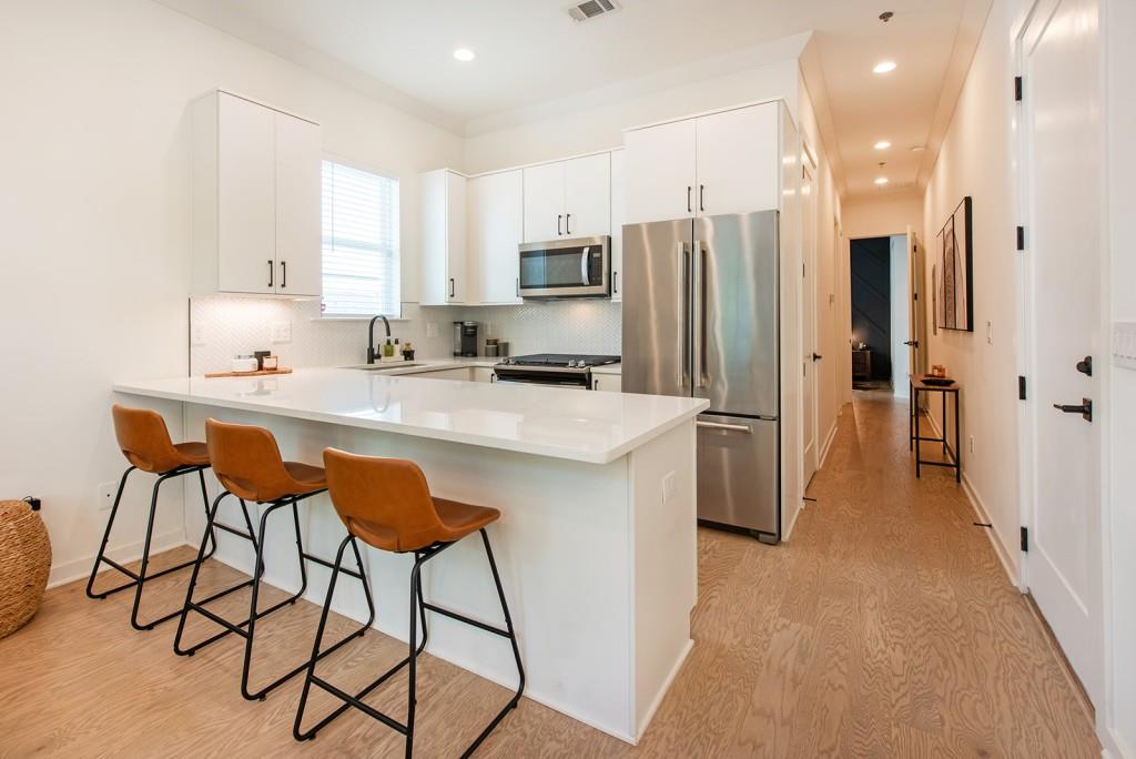 417 East College Avenue, Unit 102 Decatur, GA 30030 - Photo 14 of 60 a kitchen with stainless steel appliances granite countertop a refrigerator a sink a stove a microwave and island with wooden floor
