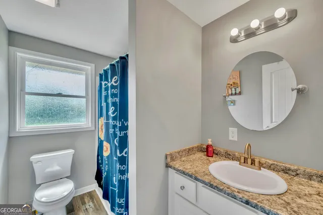 a bathroom with a granite countertop toilet a sink and a mirror