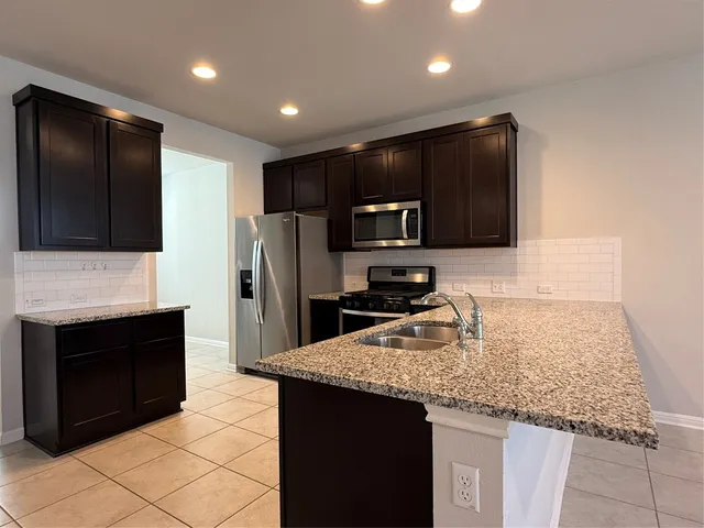 a kitchen with granite countertop kitchen island cabinets stainless steel appliances and a counter space