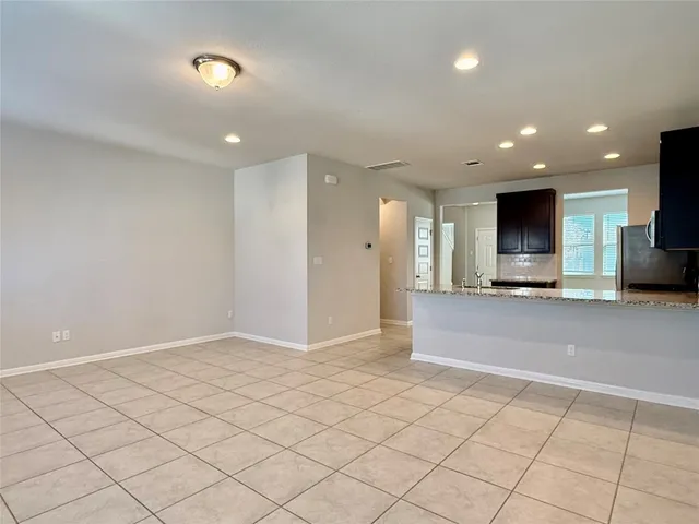 an empty room with kitchen view and windows