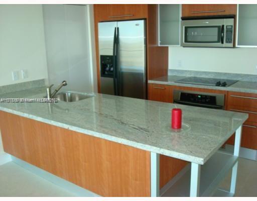 a kitchen with stainless steel appliances granite countertop a sink and a refrigerator