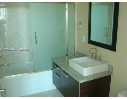 185 Southwest 7th Street, Unit 2207 Miami, FL 33130 - Photo 3 of 8 a bathroom with a sink a toilet a mirror and bathtub
