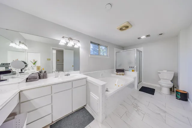 a large white bathroom with a double vanity sink and mirror