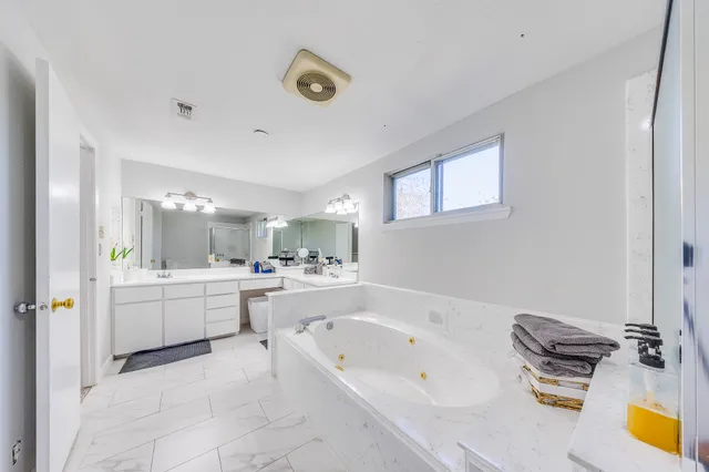 a large bathroom with a tub a sink and a mirror