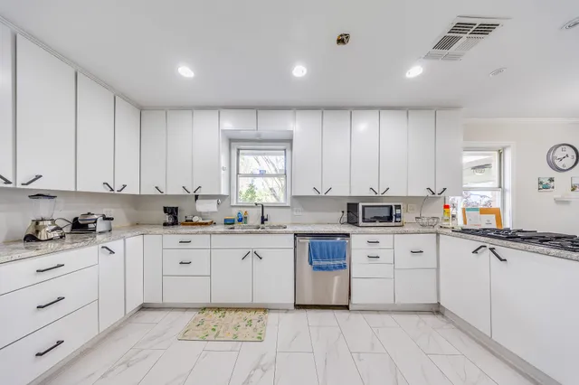 a large white kitchen with stainless steel appliances granite countertop a stove and white cabinets
