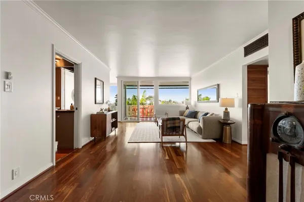 a living room with furniture a large window and wooden floor