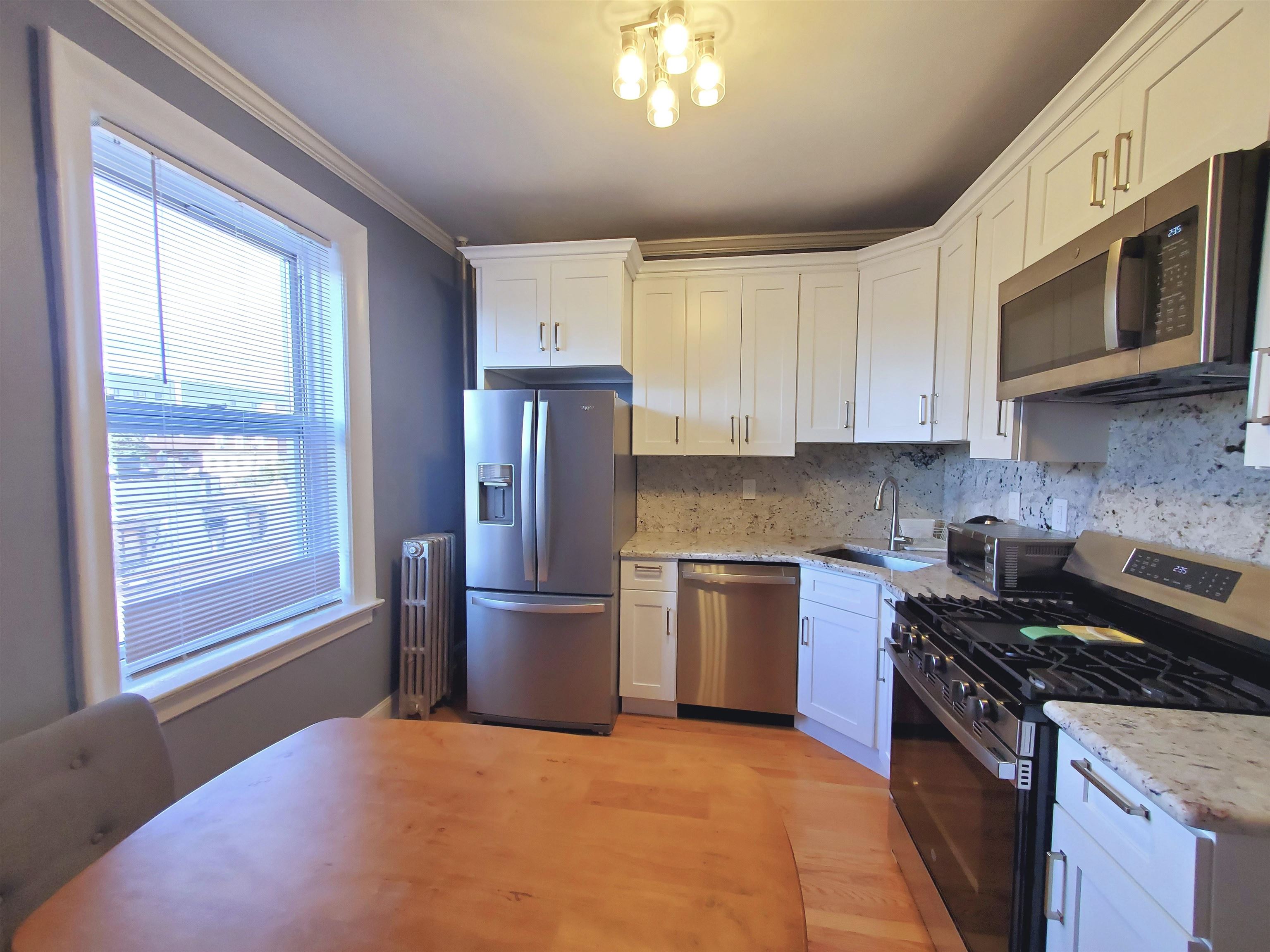 6701 Boulevard East, Unit E4 West New York, NJ 07093 - Photo 7 of 12 a kitchen with stainless steel appliances granite countertop a stove top oven a sink dishwasher a refrigerator and a microwave