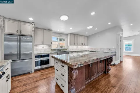 a kitchen with kitchen island a counter top space a sink stainless steel appliances and cabinets