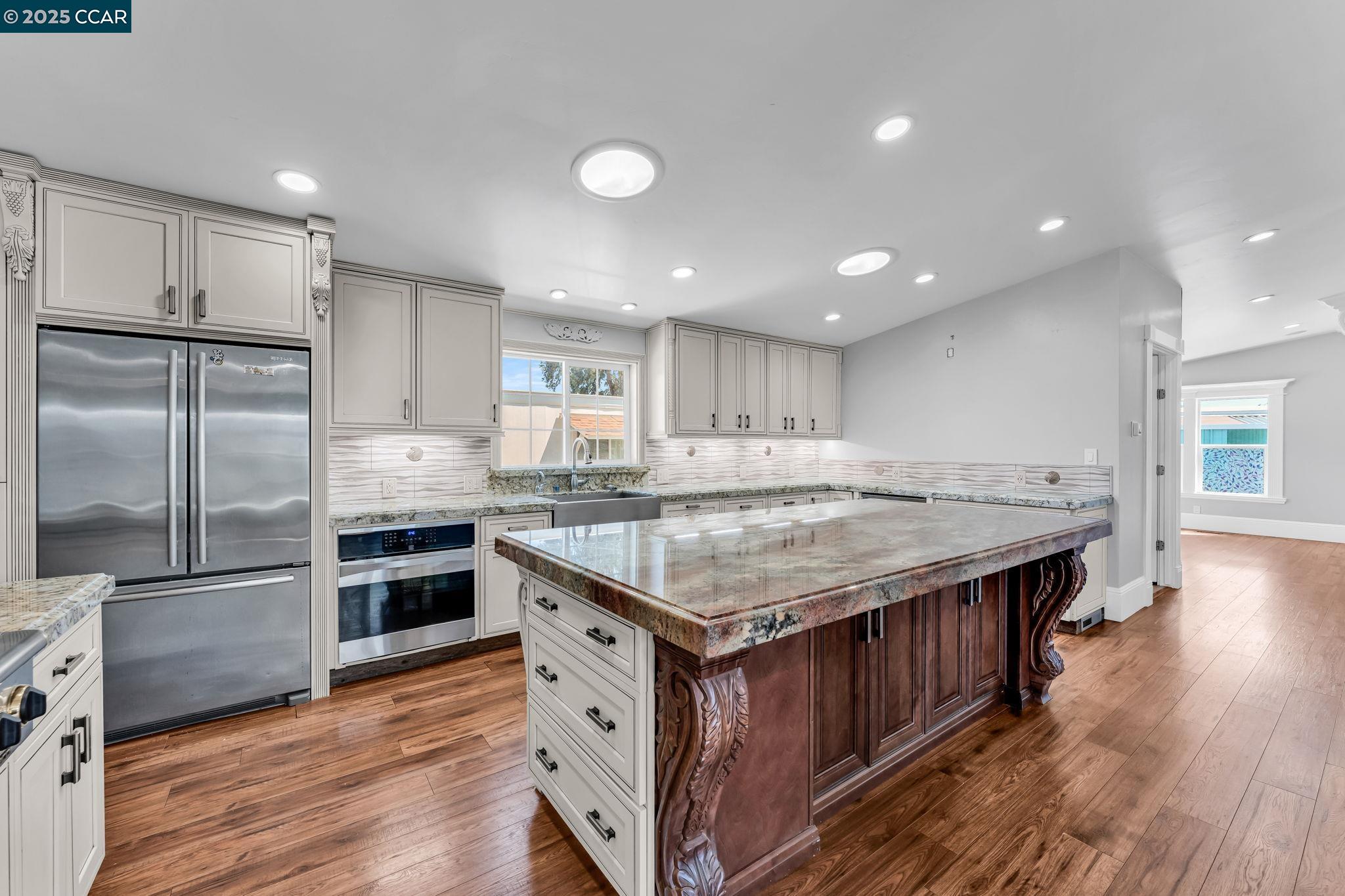 a kitchen with kitchen island a counter top space a sink stainless steel appliances and cabinets