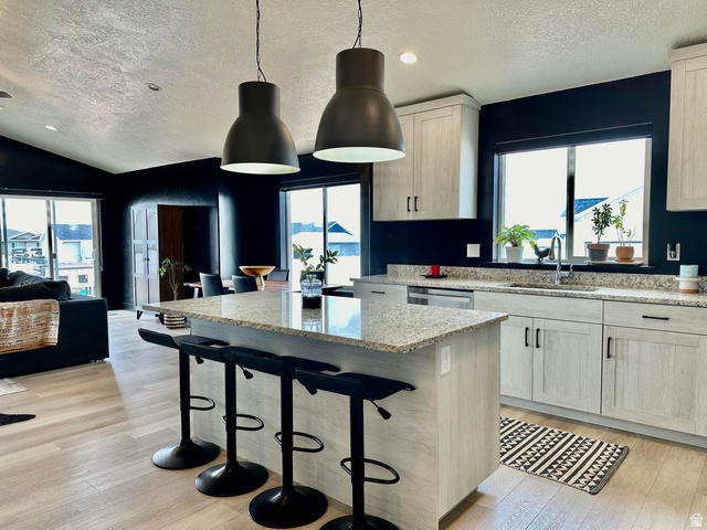 4349 Half Mile Road East Enoch, UT 84721 - Photo 36 of 36 Kitchen featuring a breakfast bar, open floor plan, a kitchen island, light stone counters, and light wood-style floors