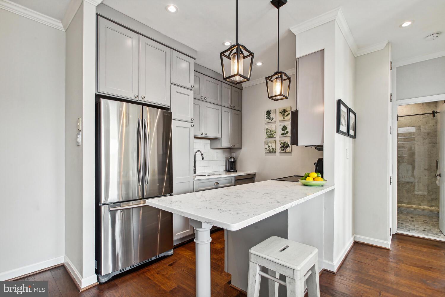 2000 16th Street Northwest, Unit 605 Washington, DC 20009 - Photo 8 of 16 a kitchen with kitchen island stainless steel appliances a table chairs sink and refrigerator