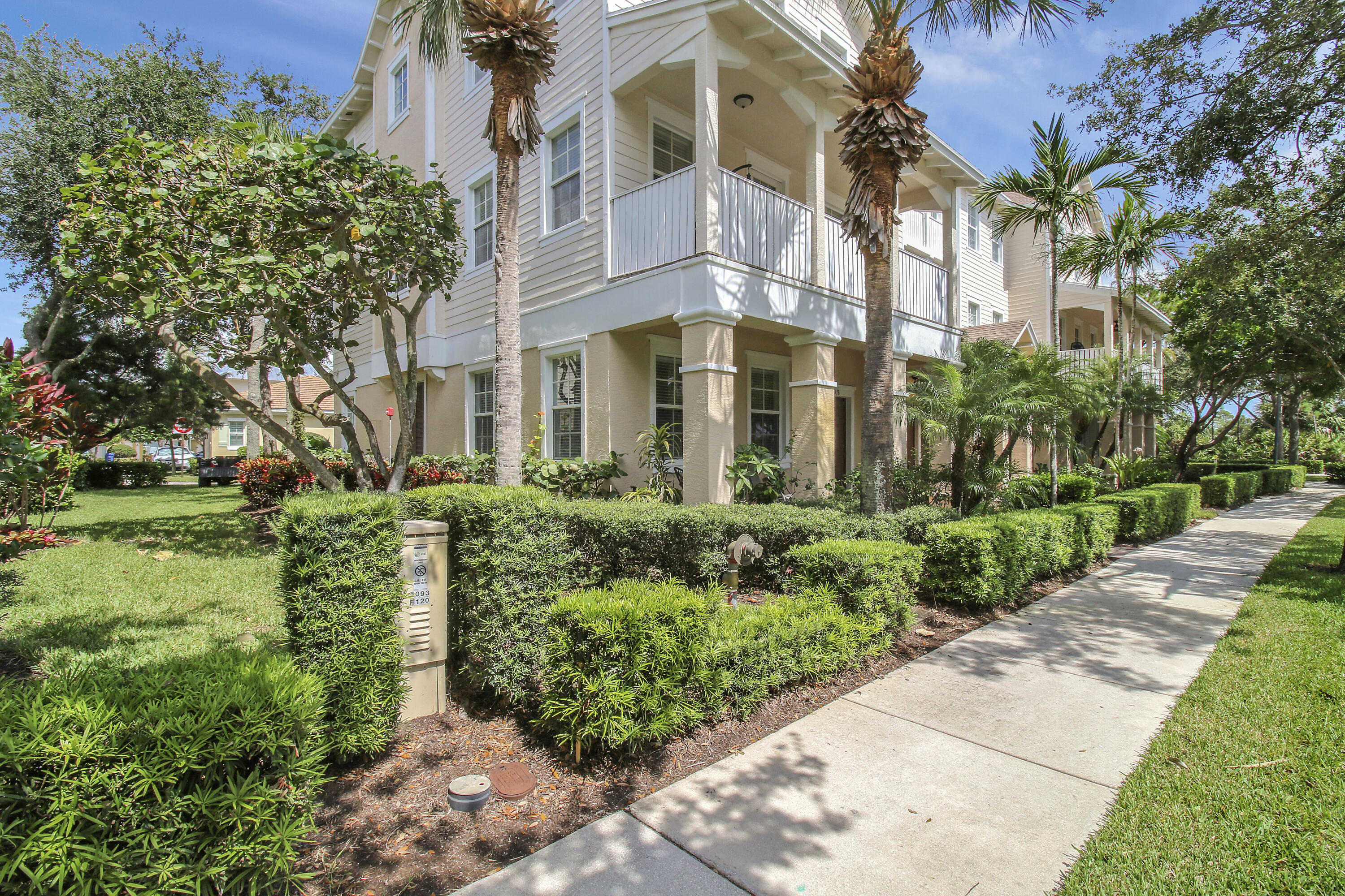 a view of a multi story residential apartment building with a yard and large trees