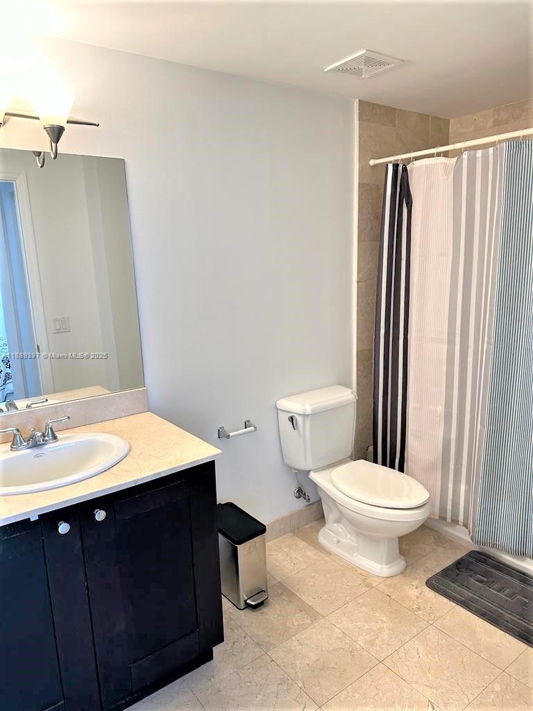 4100 Salzedo Street, Unit 702 Coral Gables, FL 33146 - Photo 3 of 15 a bathroom with a sink a toilet a mirror and shower curtain