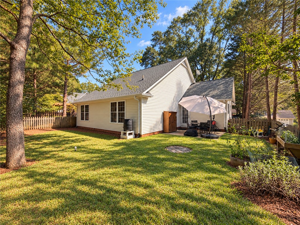 113 Grand Oak Circle Pendleton, SC 29670 - Photo 22 of 25 Mature trees frame a grassy lawn behind this classic vinyl-sided home with a patio space.