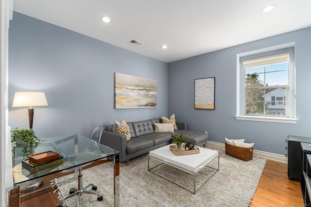 a living room with furniture and a lamp on table with wooden floor
